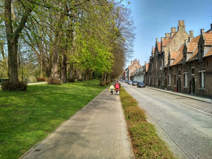 a small road with a line of homes and people walking down it