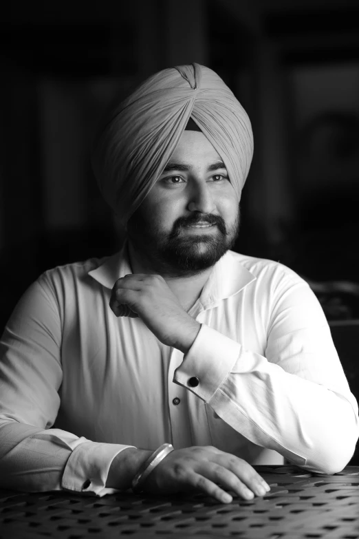 man sitting at table in front of camera wearing turban