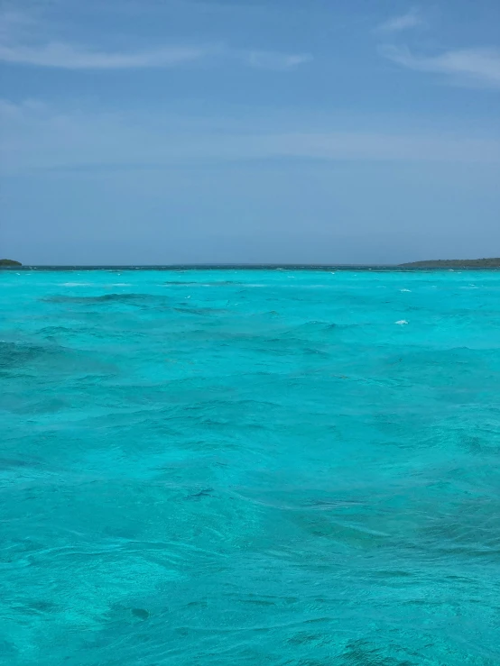 a single boat in blue water against a blue sky