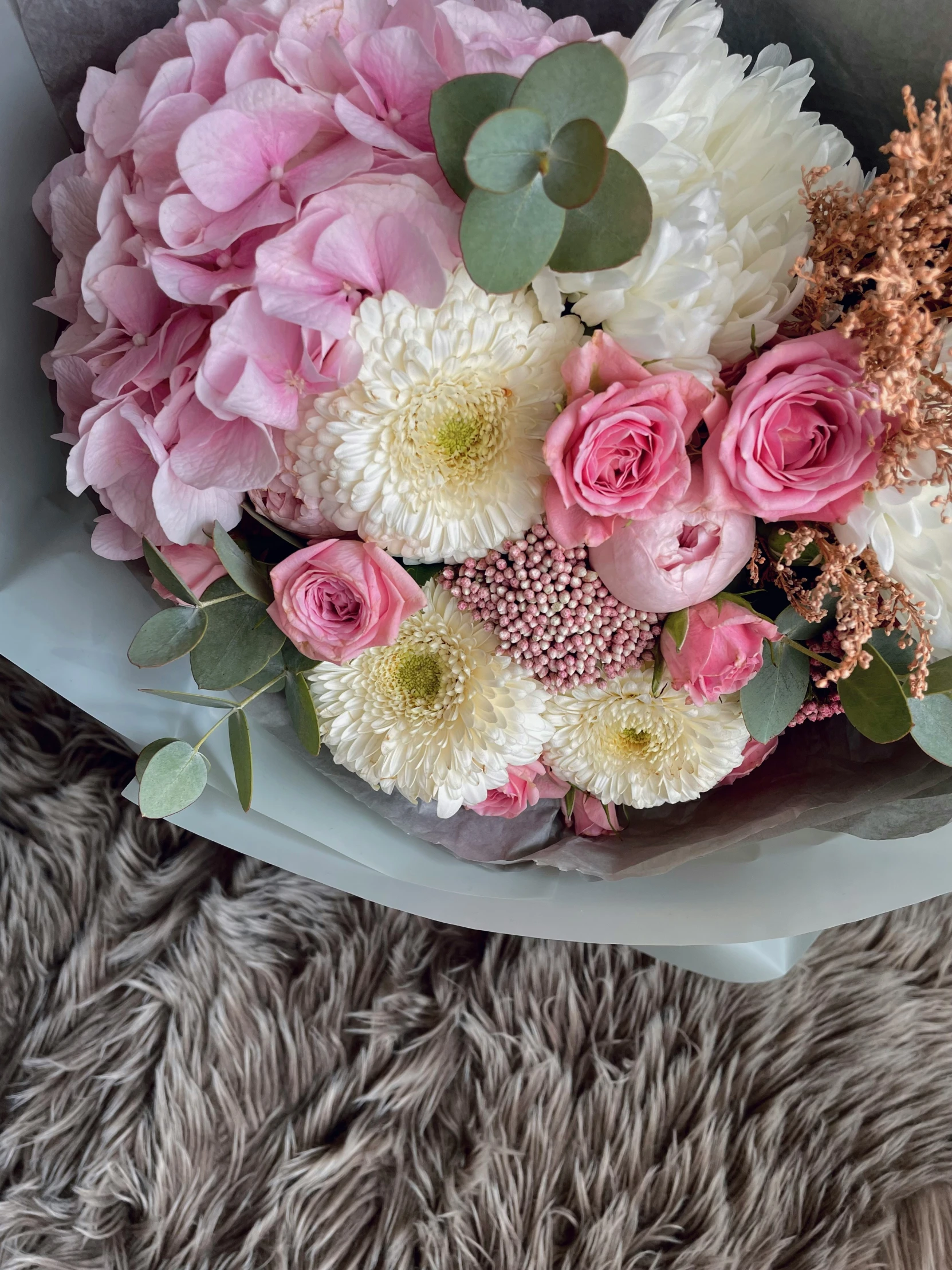 a bouquet of pink and white flowers on a brown surface