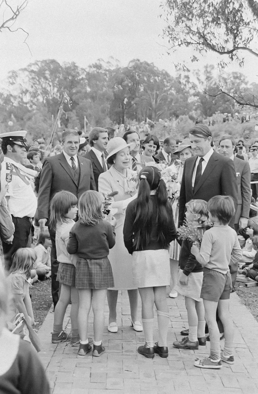 an old pograph of a couple of men shaking hands with children