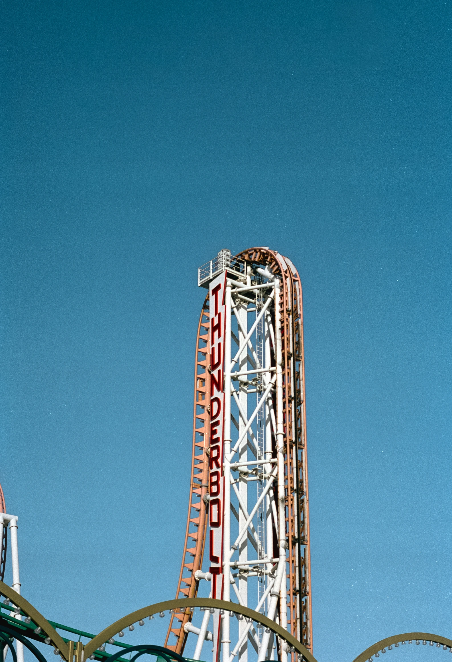 the roller coaster at an amut park is looking upward