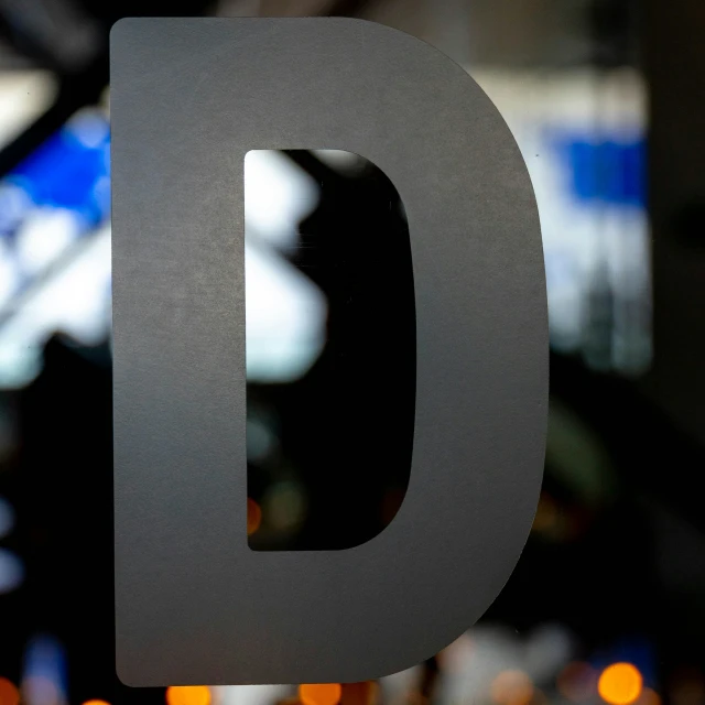 a black metal letter d on a glass surface