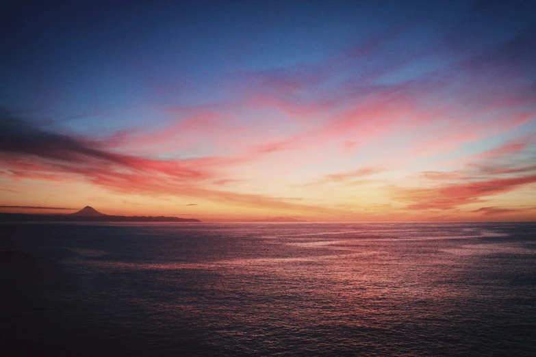 sunset with large cloud in the sky over a bay