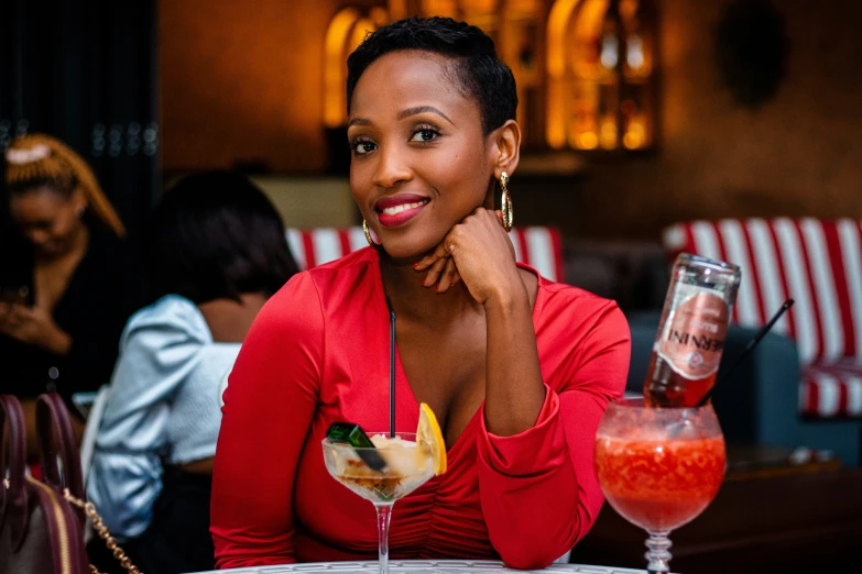 a woman in a red shirt is sitting at a table and smiling