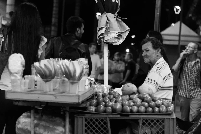 people at an outdoor market selling fruits and vegetables