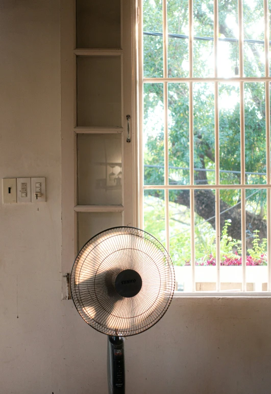 a fan sitting underneath a window on top of a table