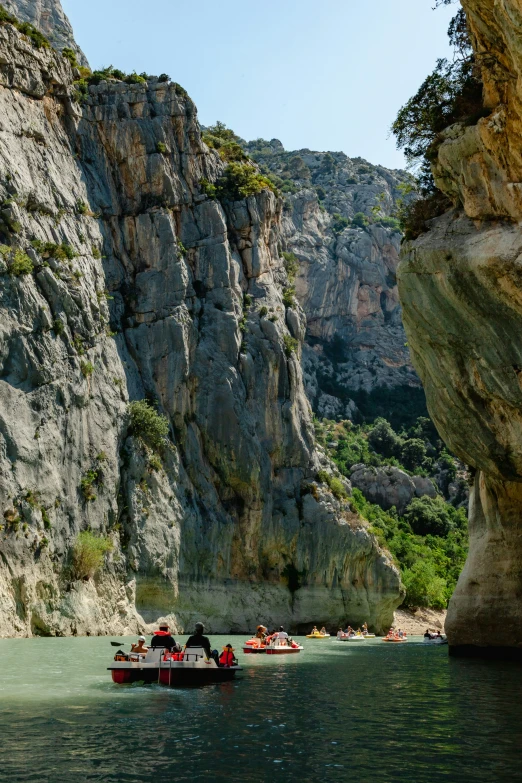 a group of people in boats in the water on a mountain side