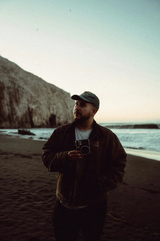 a man wearing a hat while standing on top of a beach