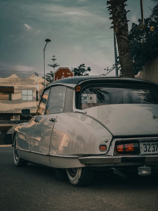 an old fashioned car parked on the street next to a tree