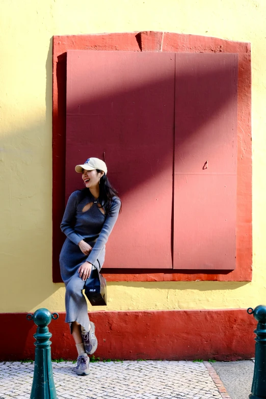 a woman sitting in front of a red window