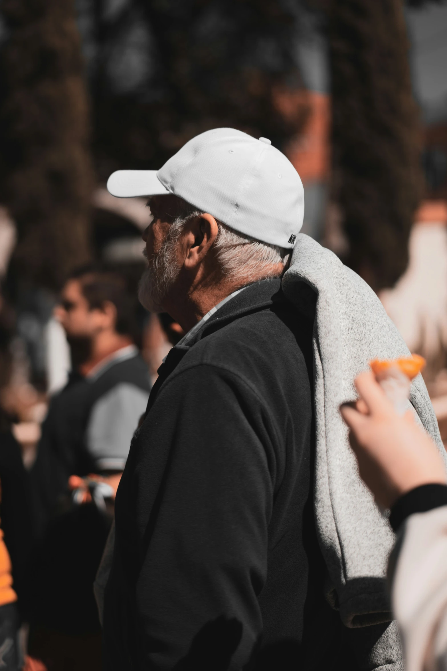 an older man with a white cap is eating oranges