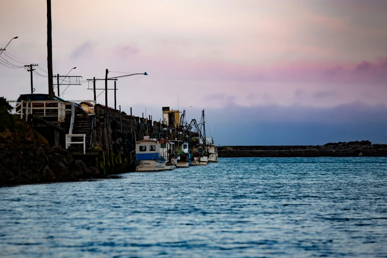 boats floating next to some stone docks during the dusk