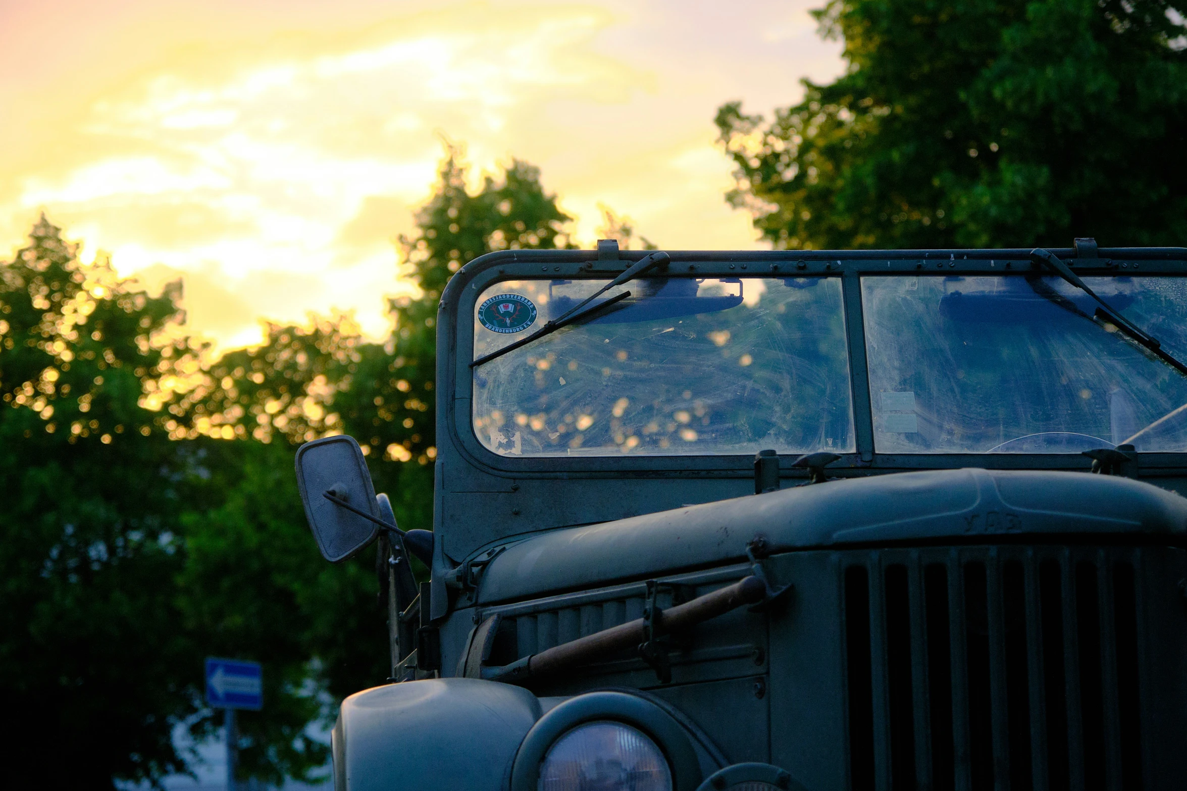 an old green truck parked in front of trees