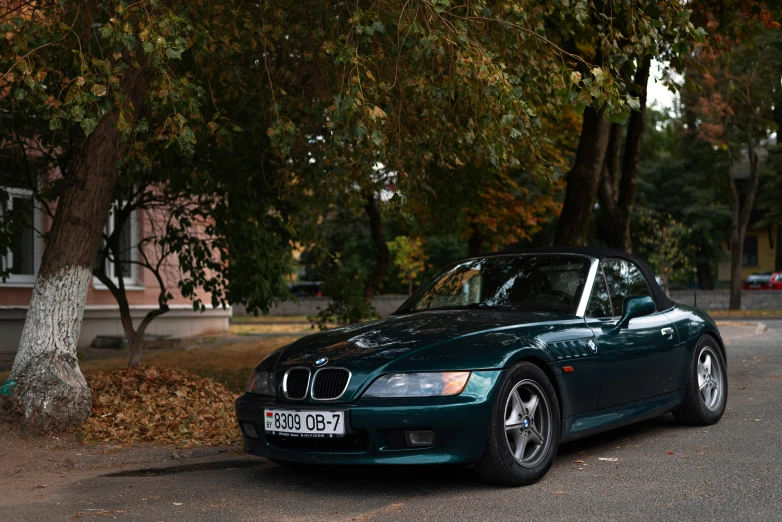 a car is parked on the street next to some trees