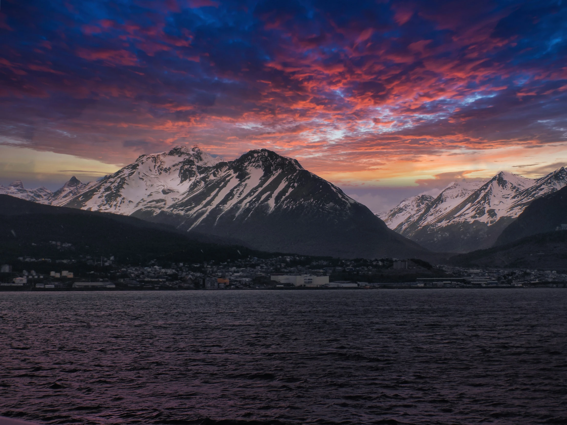 a mountain range with snow capped mountains in the distance at dusk