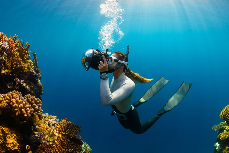 a man swimming in the ocean holding a helmet and scuba gear