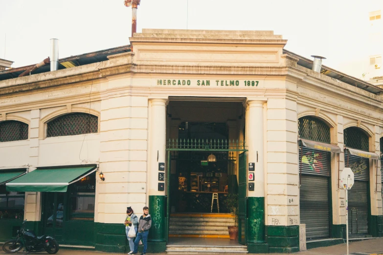 people standing outside the entrance to a building with a sign on it