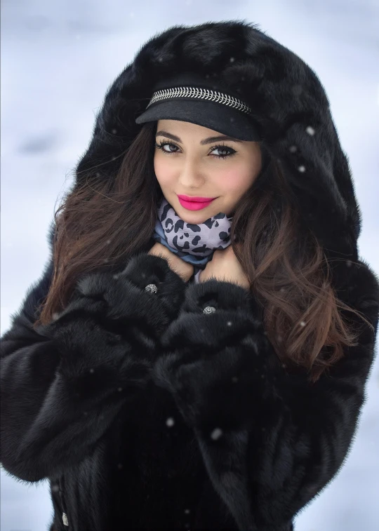 a woman in the snow with a scarf on and a hood up