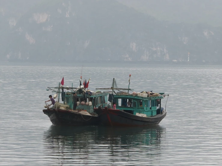 two boats sitting in the water with mountains in the background