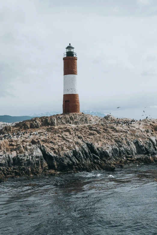 a small lighthouse stands atop a rocky outcropping