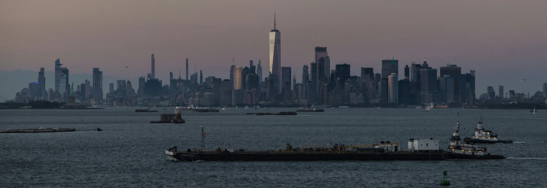 a boat floating in the ocean near the city skyline