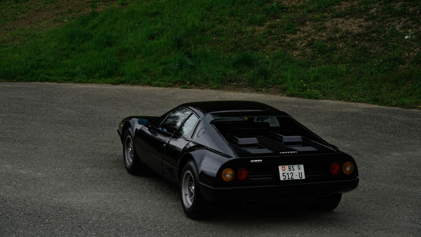 a small black car driving down a road