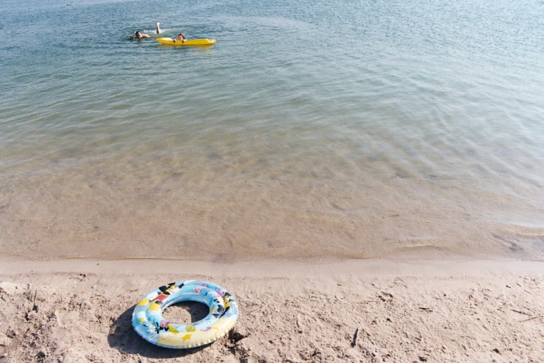 an inner tube floats in the water on a sandy beach