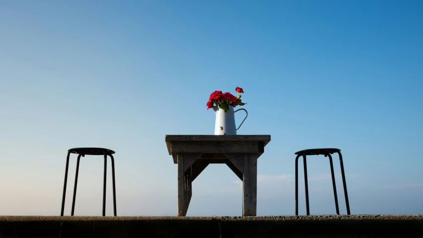 an arrangement of flowers in a vase on top of a table near four chairs