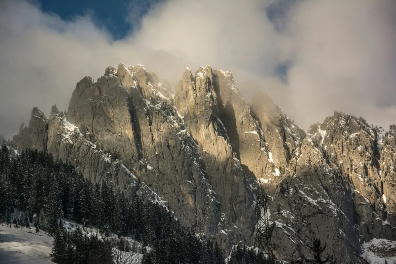 an extremely cloudy mountain with snow and trees