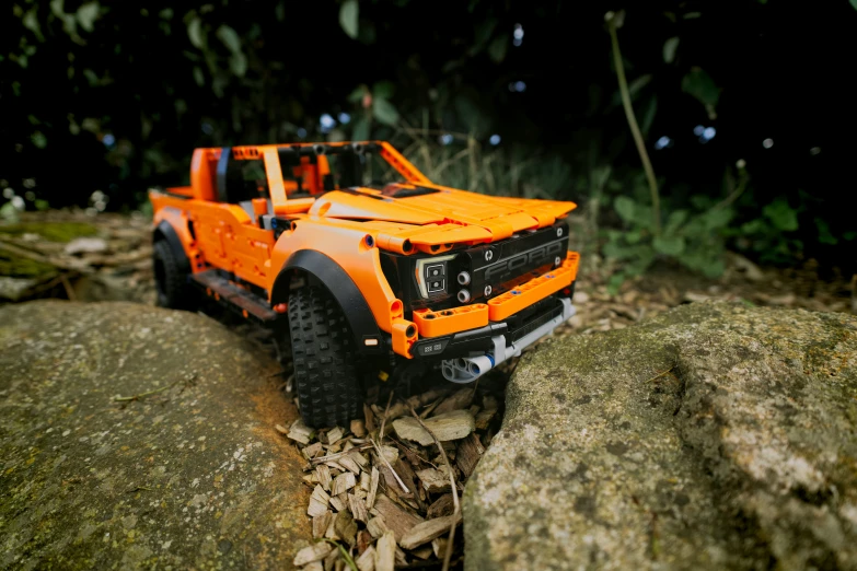 an orange toy truck sitting on a rock