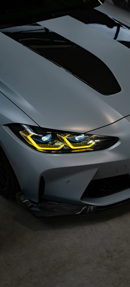 close up of a shiny gray car with a yellow halo around the lights