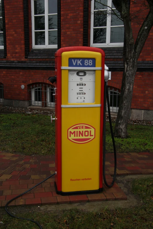 a yellow and red gas pump on brick walkway