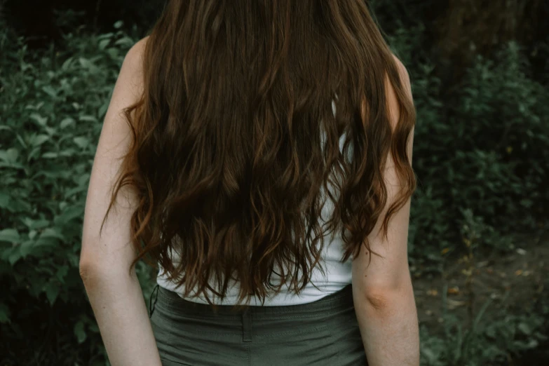 the back of a woman's head as she sits in the woods