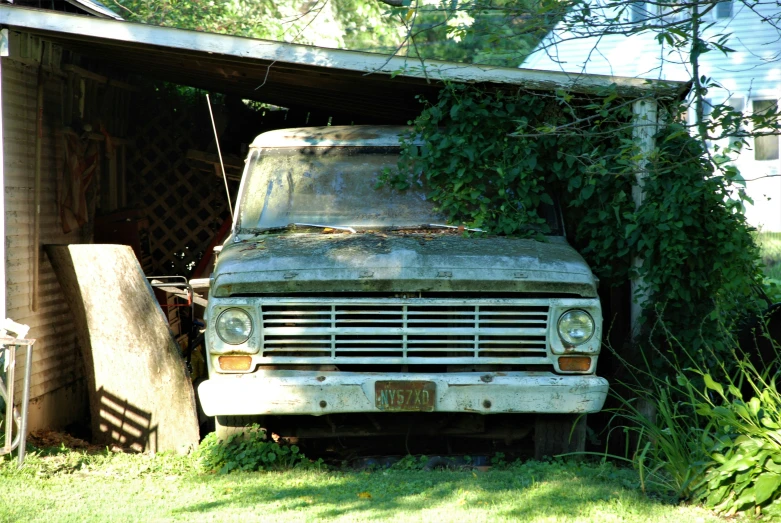 an old truck and some grass next to a building