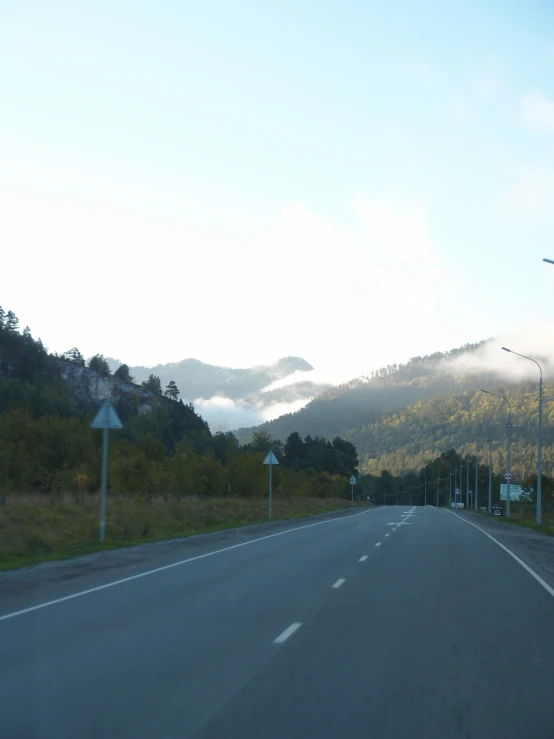 the empty road goes into a distance that is filled with fog