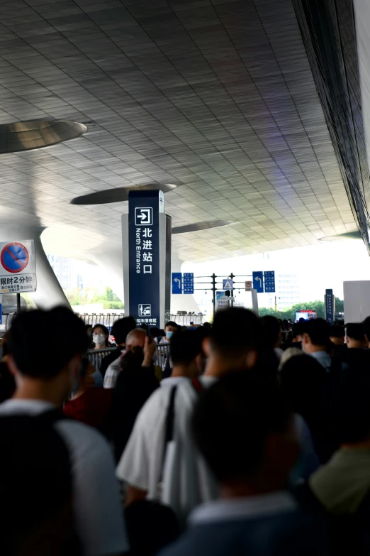 people at an airport under a building holding umbrellas