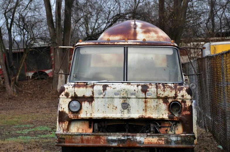 an old rusty truck parked in a fenced yard