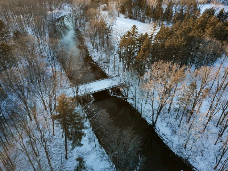 a snowy covered forest, looking down at an aerial view of a creek