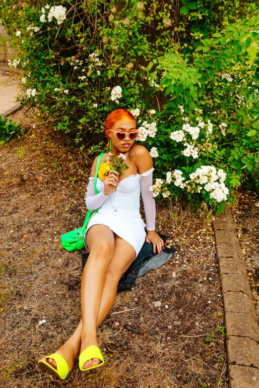 a young woman is sitting by some flowers