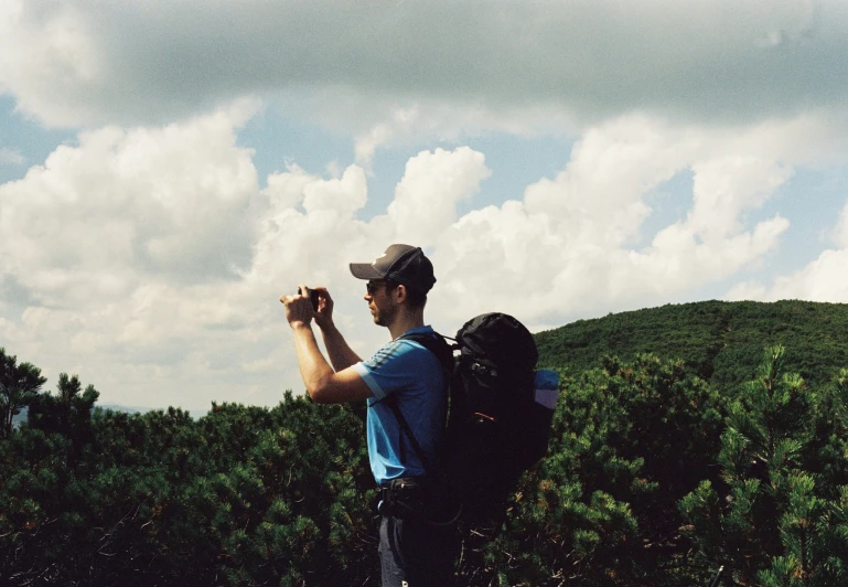 a man standing outside in a field with backpack on