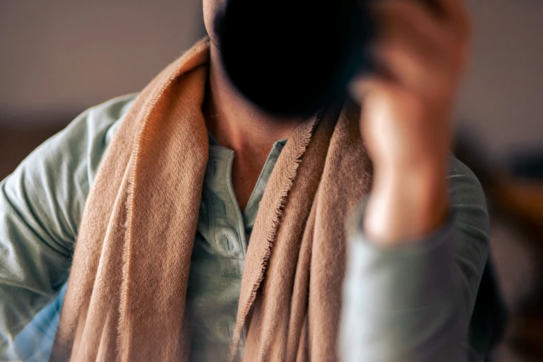 a woman holding a cellphone up with a scarf