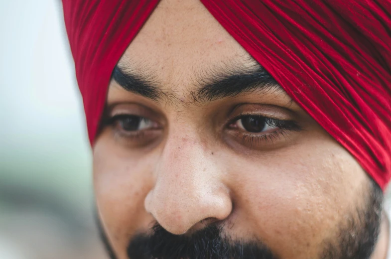 an indian man with a red turban is looking over his shoulder