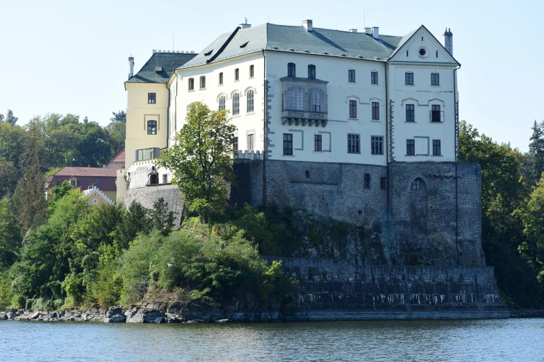 some trees water buildings and a castle style house