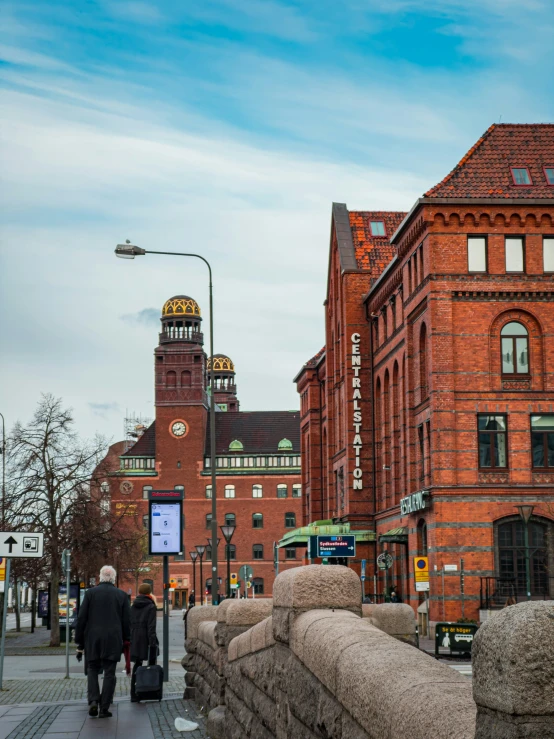 two people walking down a street next to tall brick buildings