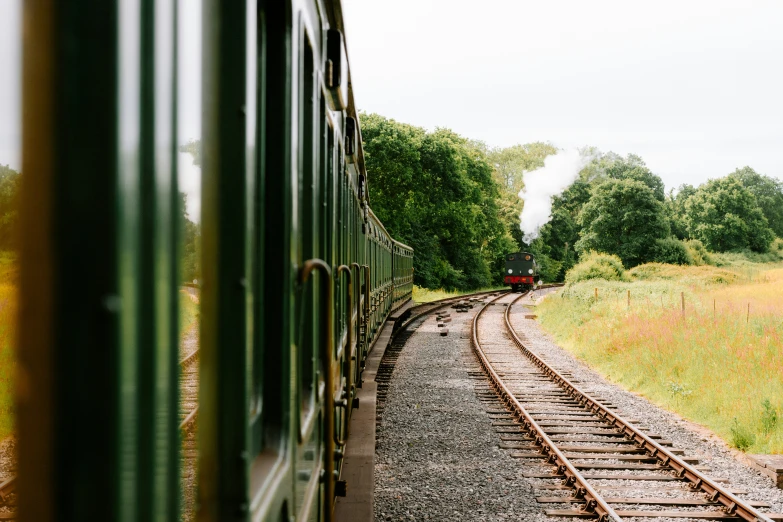 a train travels down train tracks near some grass and trees