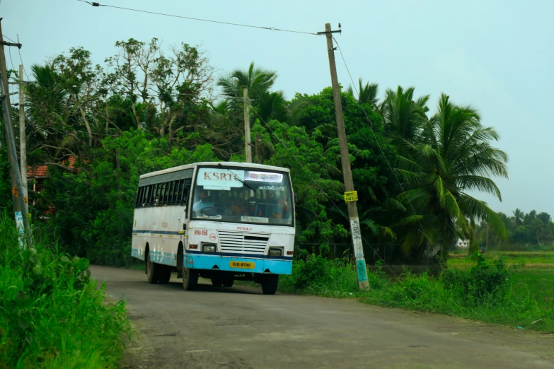 a white bus riding on top of a dirt road