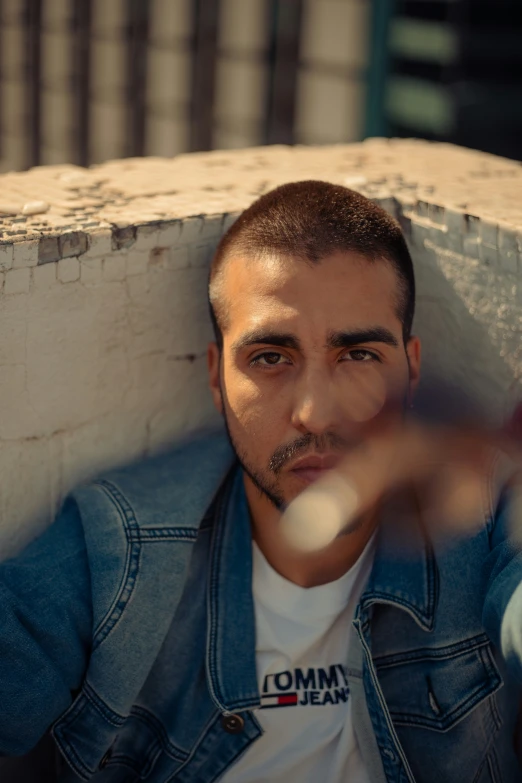 a young man looks into the camera from behind a ledge