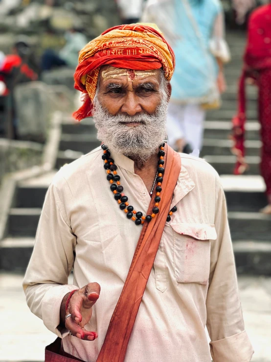 a person in traditional clothing and red turban holding a handbag