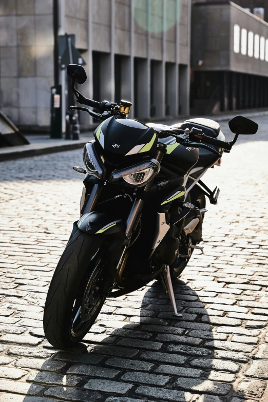 a black and yellow motor bike on top of cobblestone